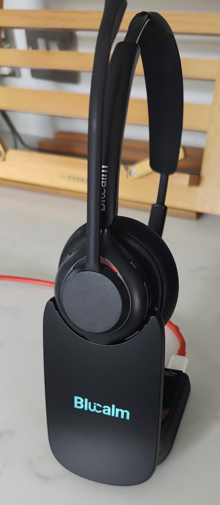 Blucalm INSIGHT50 headset on its dock, with a cyan illuminated Blucalm branded faceplate